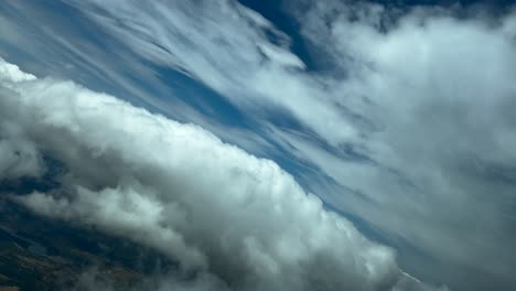 immersive pilot pov flying through some fluffly clouds in a real time flight late in the afternoon, with a deep blue sky