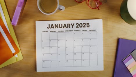 woman reviewing january 2025 calendar at her desk