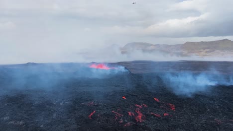 Der-Hubschrauber-Fliegt-über-Den-Vulkan-Fagradalsfjall,-Während-Rauch-Und-Dampf-über-Der-Kargen-Schwarzen-Landschaft-Aufsteigen