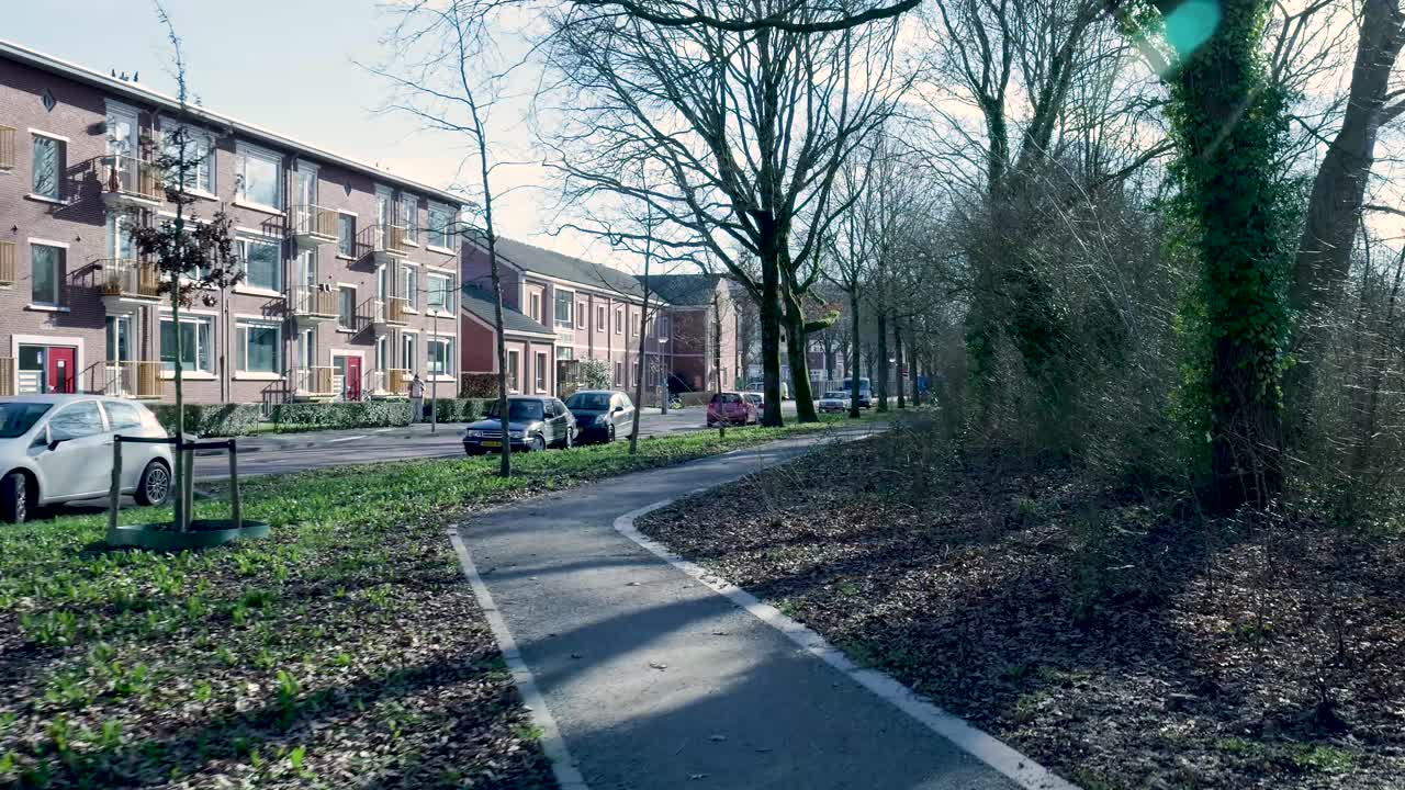Beboelsesgade med lejlighedsbygninger og bypark på en solskinsdag