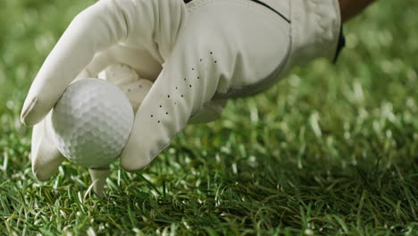 cerca de la mano con el guante sosteniendo la pelota de golf en la hierba, copiar el espacio, cámara lenta.