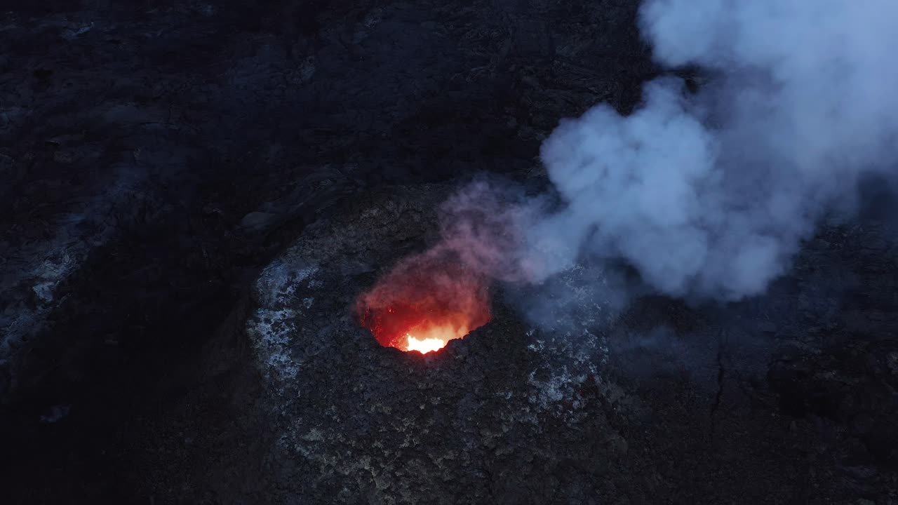 Active magma pit with smoke rising from opening, dark basalt surface