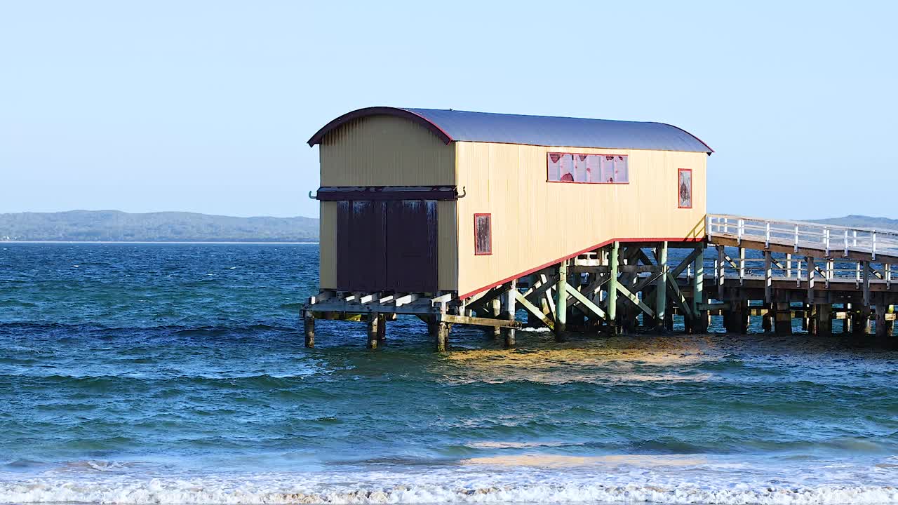 A serene view of a pier house over calm ocean waves, captured in bright daylight at Bellarine Peninsula, Victoria