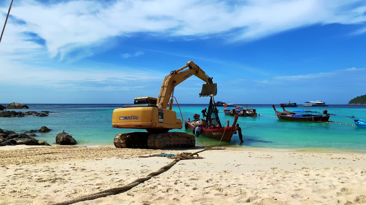A shot of an excavator with men working by the beach.