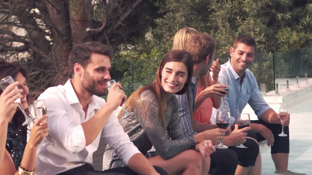 Amici felici che bevono a bordo piscina