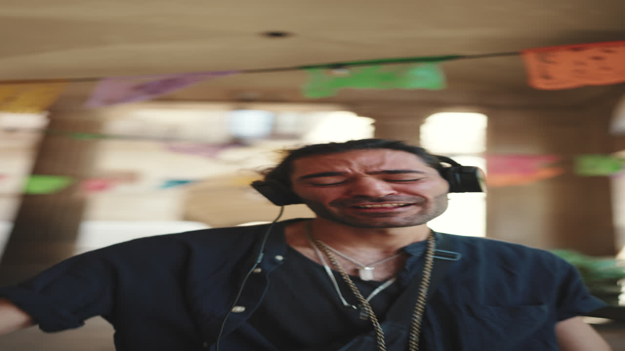 A man with headphones smiles in an archway with decorations