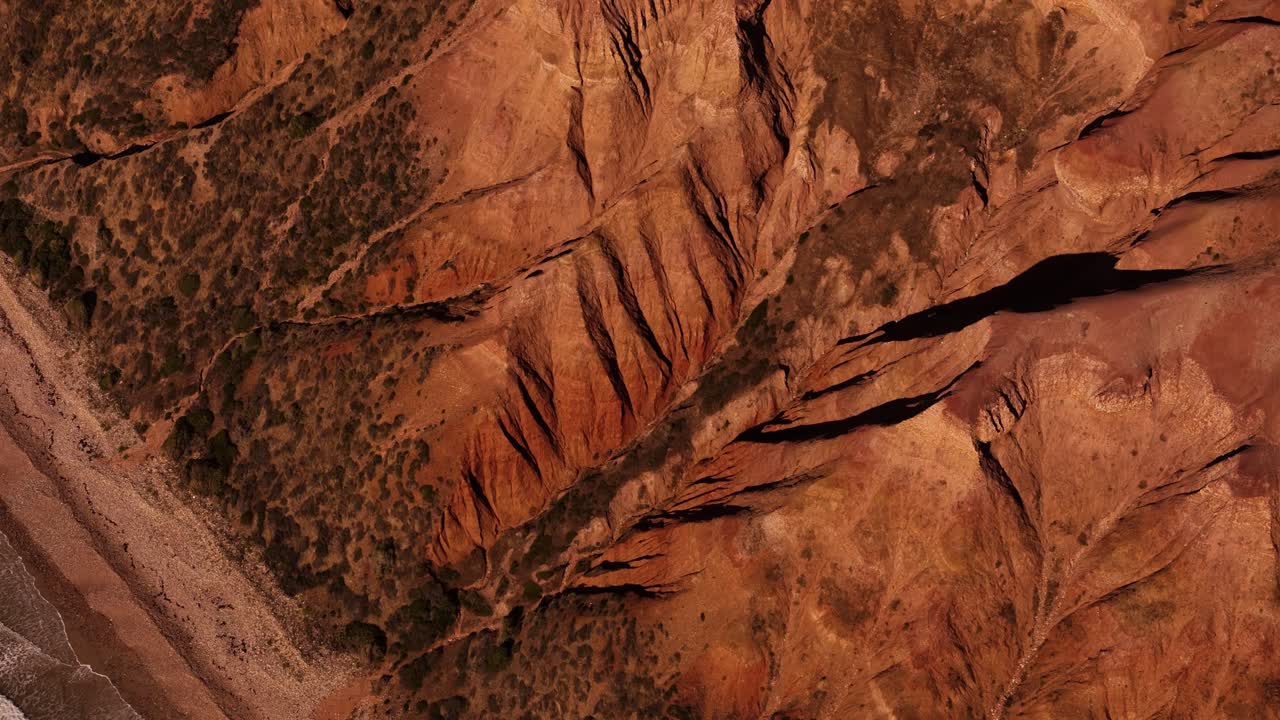 Immagine aerea astratta di vallate di terra rossa screpolata che mostra profonde fessure e motivi di pietra erosa, tipico paesaggio australiano