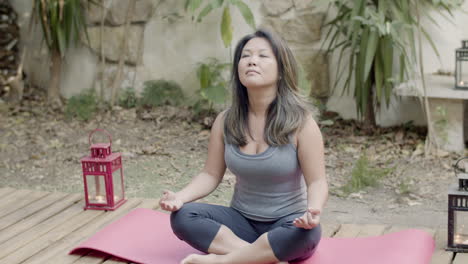 long shot of carefree japanese woman meditating in backyard