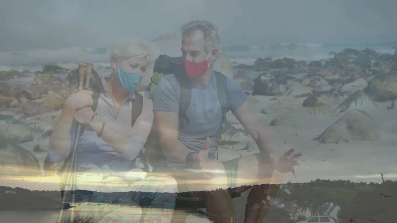 hiking couple exploring rocky ocean shoreline for travel while animated graph floating overhead