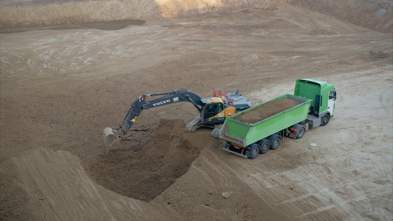 Excavator Arranging and Leveling Dirt in Dump Truck After Loading to Maximize Load Capacity and Stability. Sitework. Preparatory work on a construction site. Excavator Loading Dirt into Dump Truck.