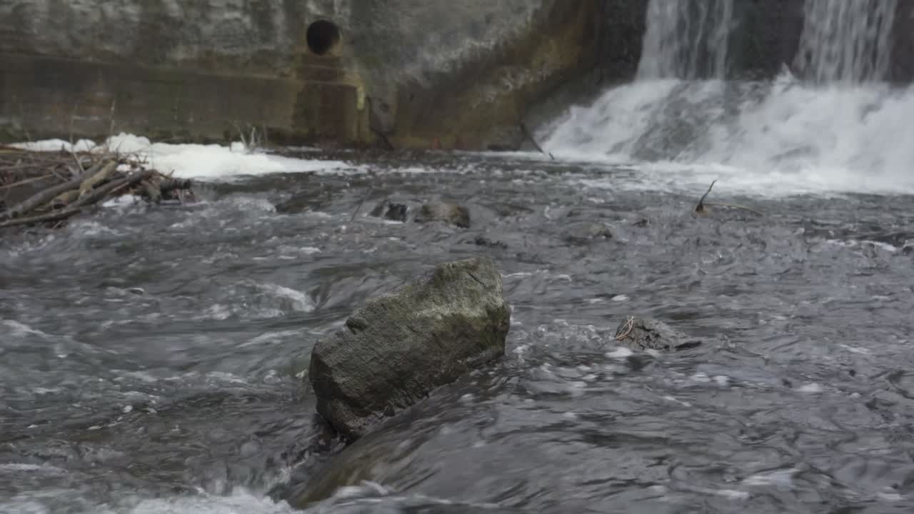 Water rushing over a waterfall at Alton Mill Dam in winter, Caledon, Ontario, Canada