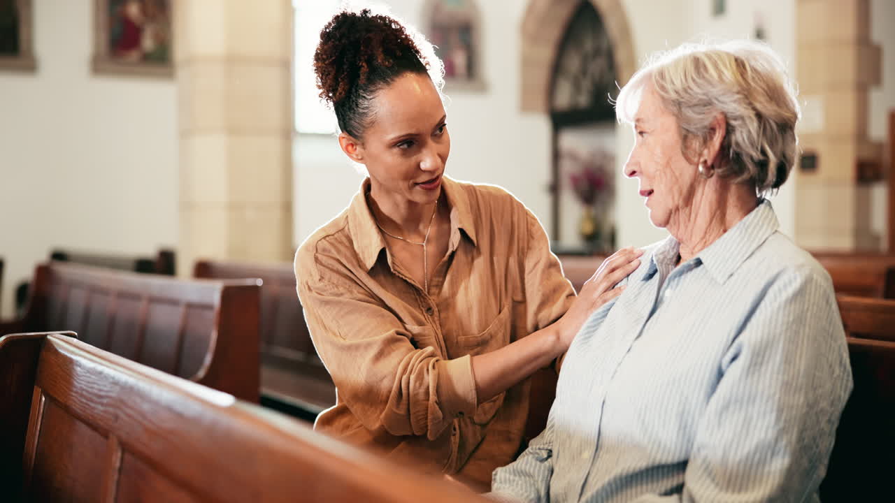 A young woman comforting an elderly woman in a church