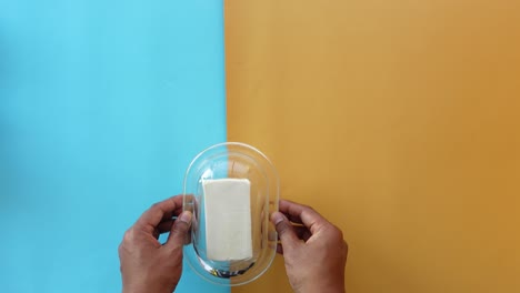 hands holding a butter dish with a stick of butter inside