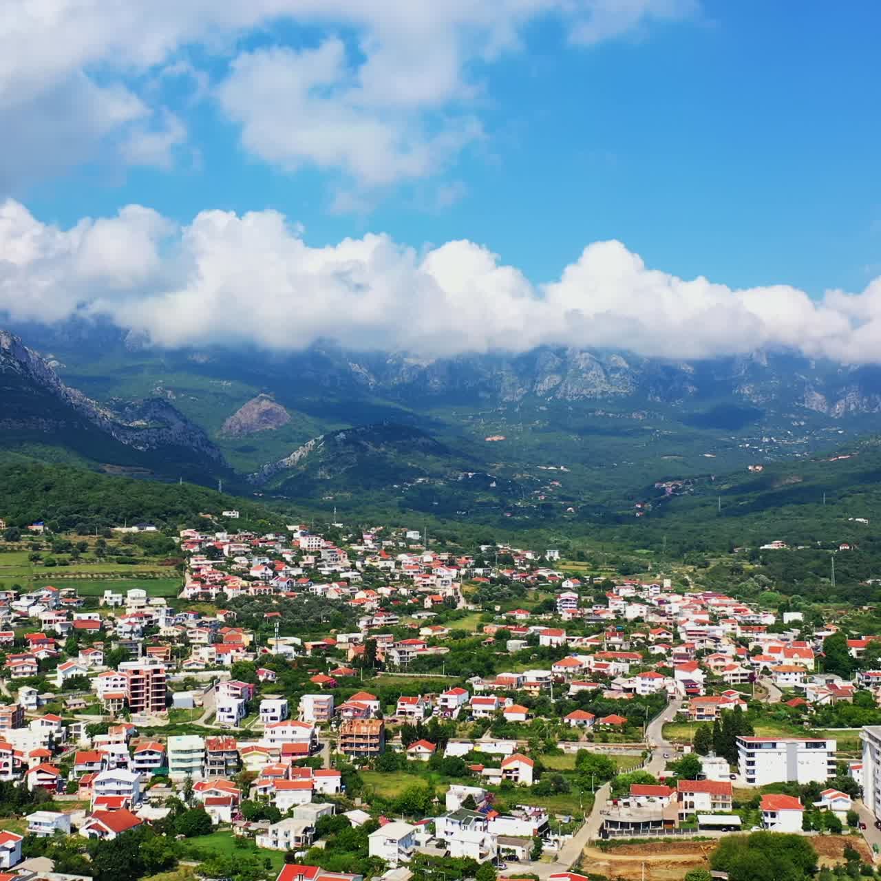 Flying above the panorama of Bar, Montenegro. Beautiful city view locating between the mountain range. Aerial perspective