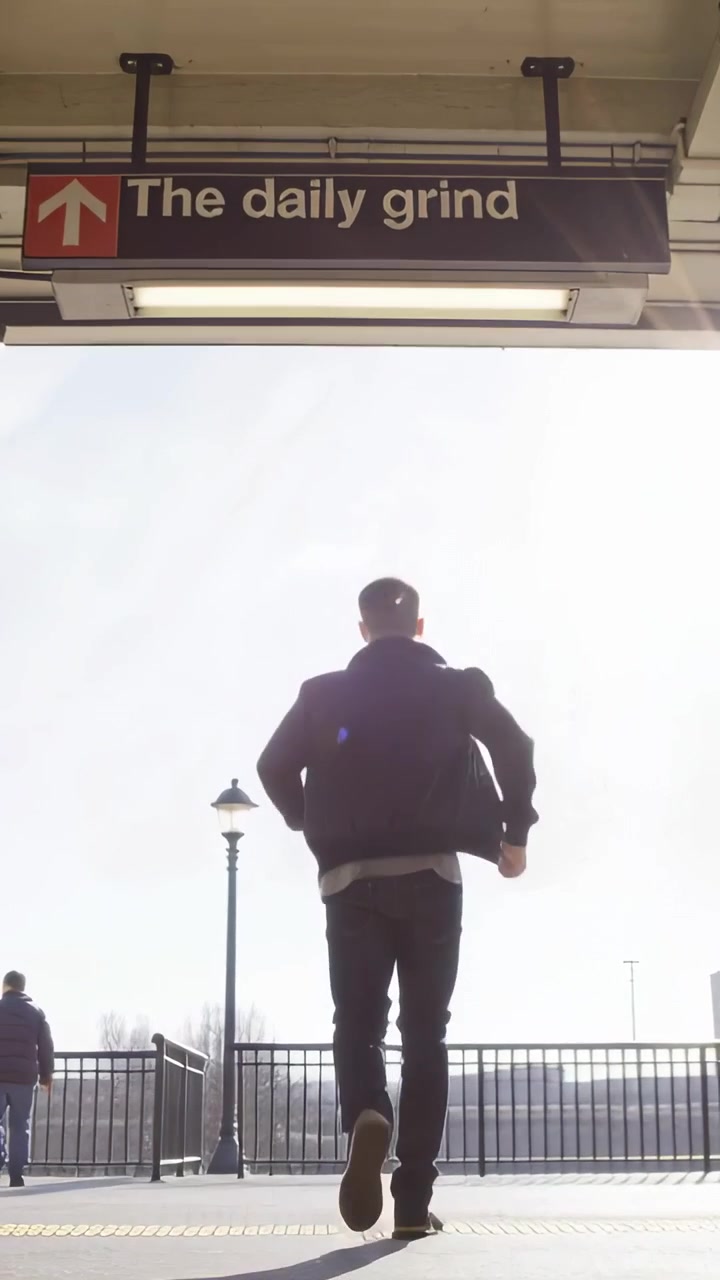 Video verticale: Un uomo in cappotto scuro scende i gradini e cammina sulla piattaforma, passando un cartello con la scritta "routine quotidiana".