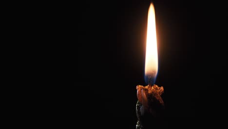 a single candle is lit on a black background. candle flame in the dark