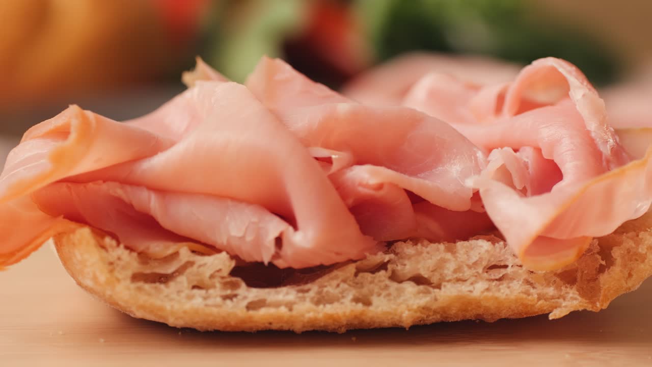 Mortadella ham sandwich, Traditional italian focaccia filled with thin pesto slices of mortadella, served by chef man in cafe restaurant. Macro of traditional italian spanish tapas antipasti.