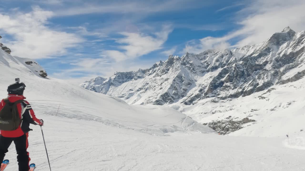 el esquiador masculino se para y mira el panorama de la cordillera en la estación de esquí de cervinia, italia