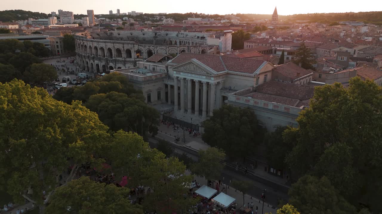 아레네스 드 니메와 그 주변의 역사적인 건물들이 해가 지는 순간, 도시의 건축적 아름다움과 문화 유산을 보여준다.