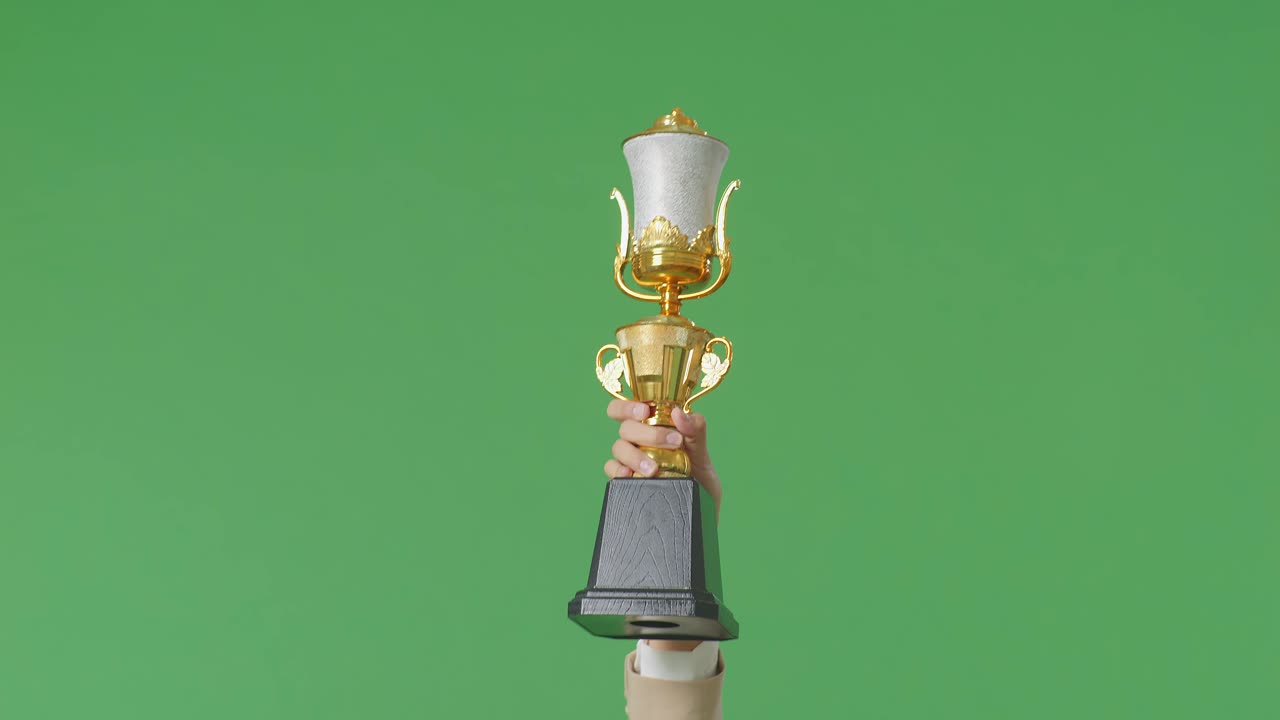 스튜디오의 녹색 스크린 배경에서 첫 번째 우승자로 우승을 축하하기 위해 공중에서 금 트로피를 들고 있는 사업 여성의 손