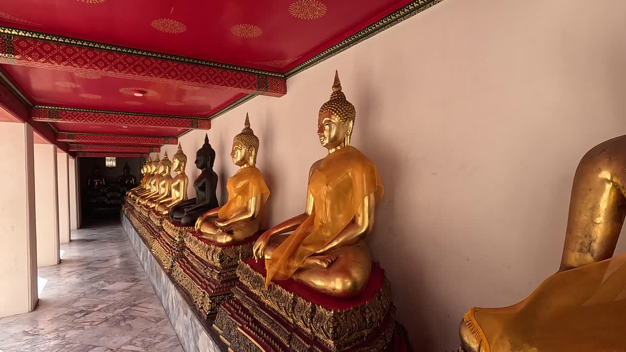 una vista tranquila de las estatuas de oro de buda en wat pho, bangkok, que muestran detalles intrincados y un ambiente sereno bajo una iluminación suave