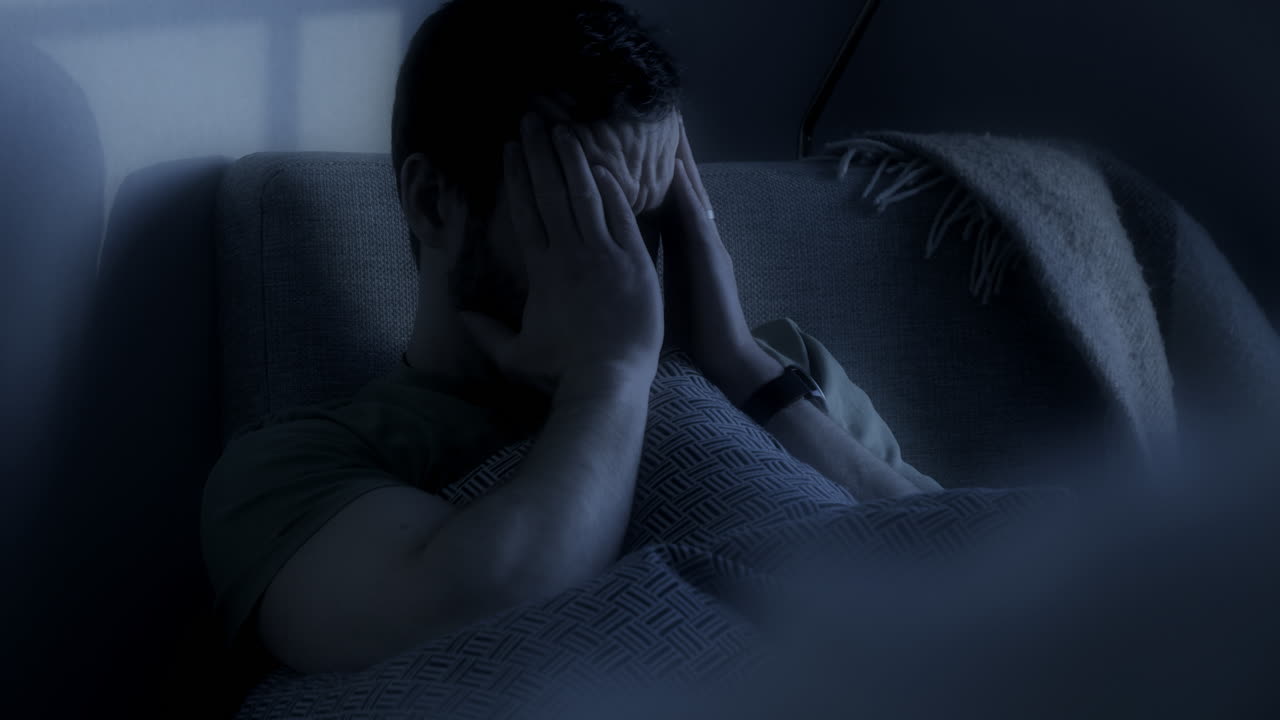 el hombre está sentado con dolor de cabeza y se está frotando la cabeza