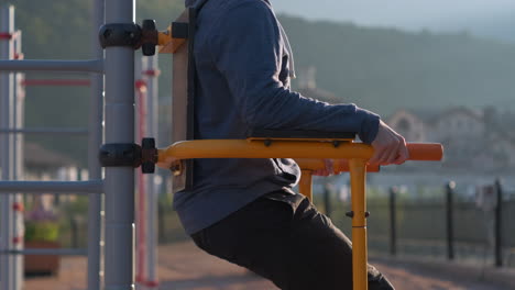 man working out on parallel bars in a park