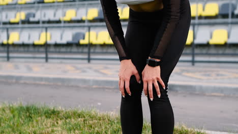 Müde-Schöne-Frau,-Die-Sich-Nach-Dem-Lauftraining-Im-Stadion-Mit-Den-Händen-Auf-Den-Knien-Ausruht