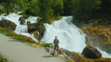 The-Traveler-Admires-The-Stormy-Mountain-River-Originating-In-The-Briksdal-Glacier-The-Majestic-Scen