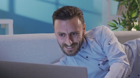 hombre guapo y elegante chateando en línea en una computadora portátil en un entorno doméstico.