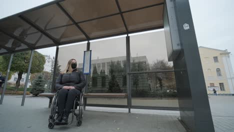 woman in a wheelchair waiting for a bus at a bus stop