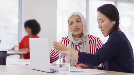 group of diverse business people using laptop and talking in office, slow motion