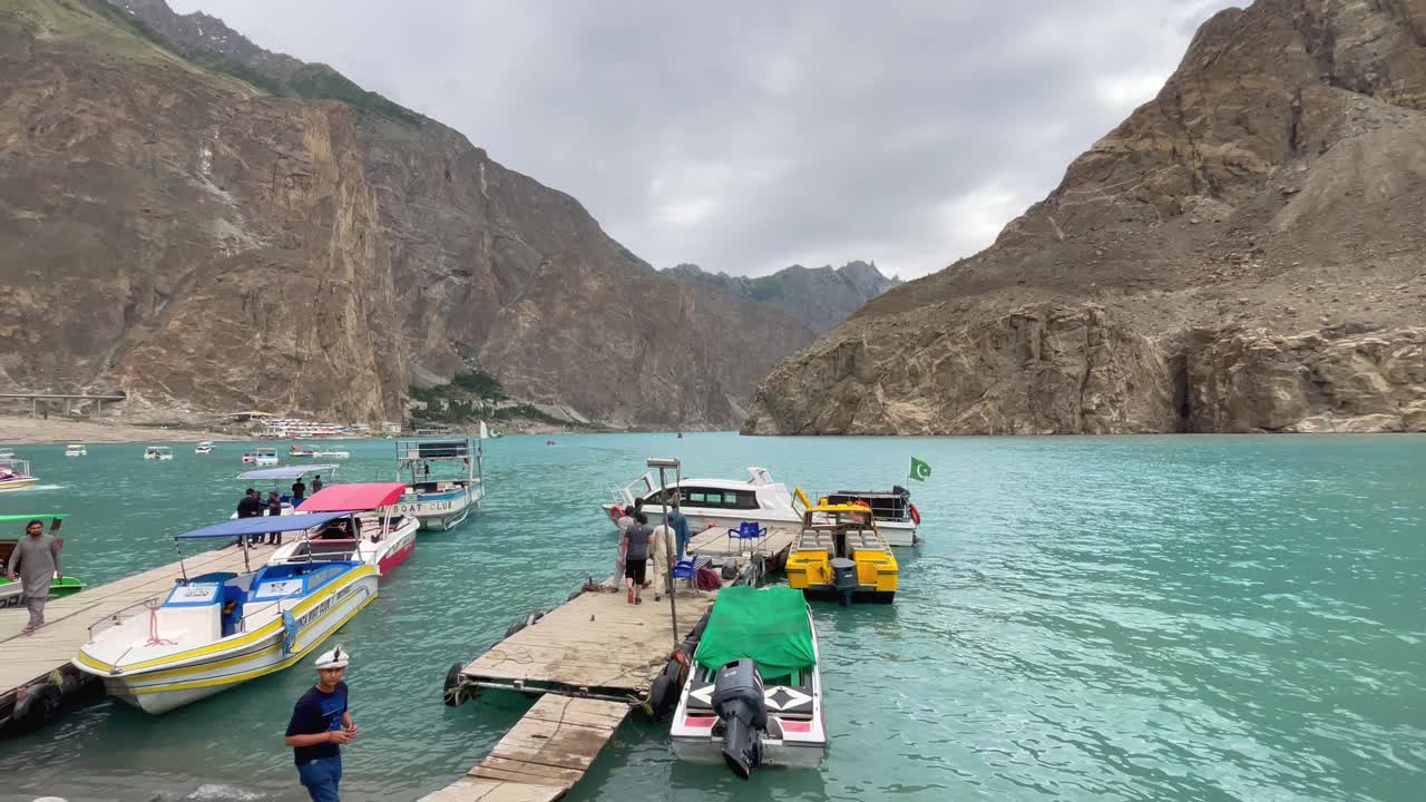 Shot of local boats halted at Attabad Lake in Hunza Valley with beautiful background of rugged hills and mountains in Pakistan.