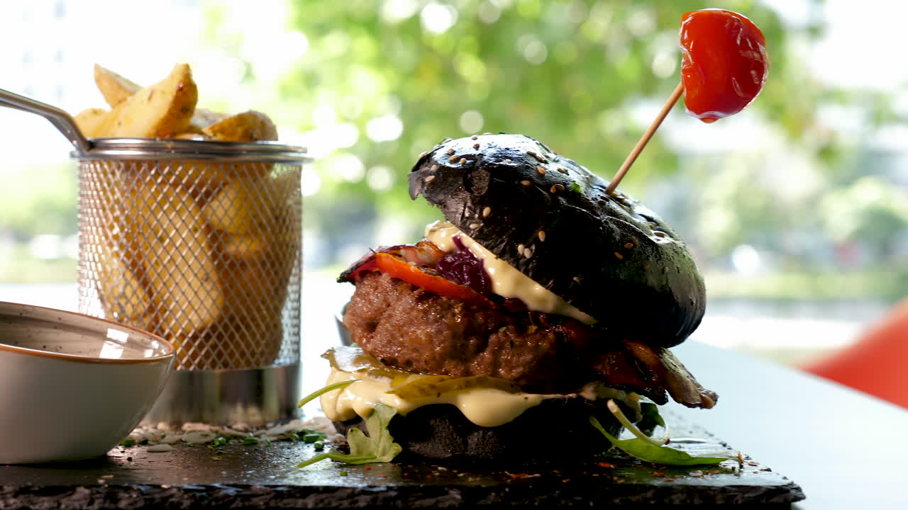 A black burger with french fries on a plate