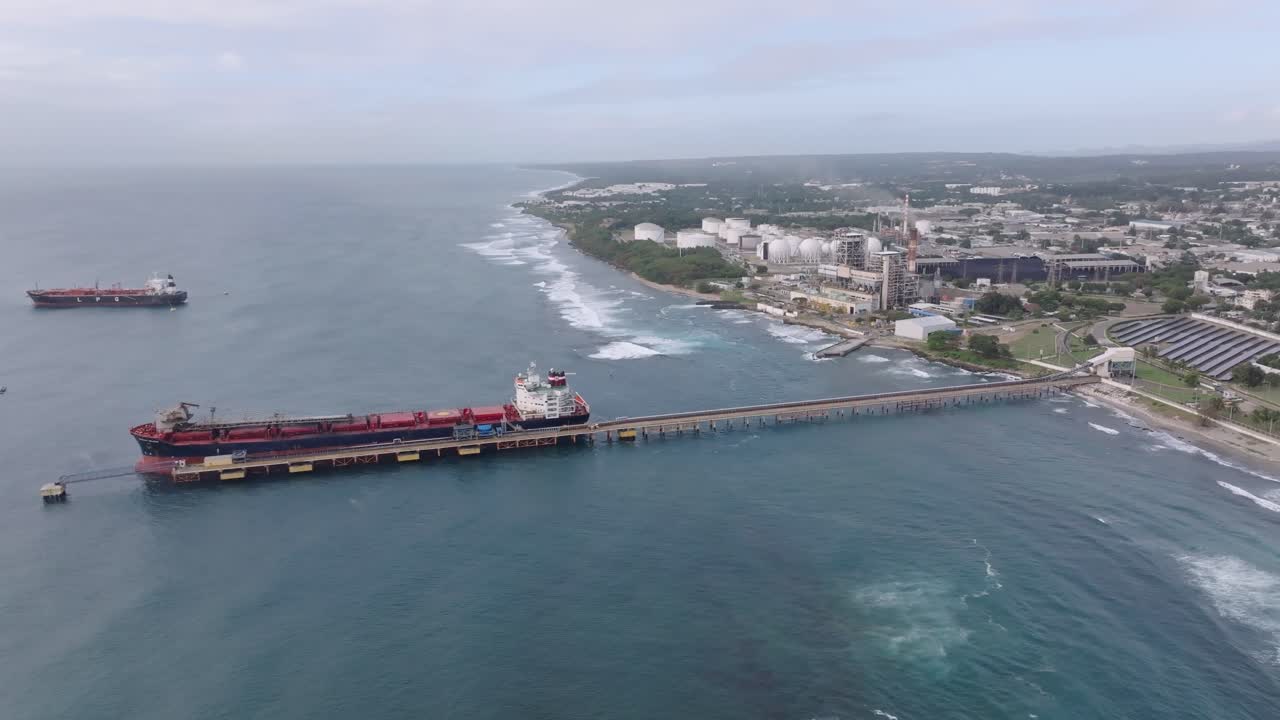 Oil tanker docked at Port of Haina with industrial infrastructure and coastline, energy distribution, maritime transport, and logistics, Dominican Republic. Aerial drone, copy space