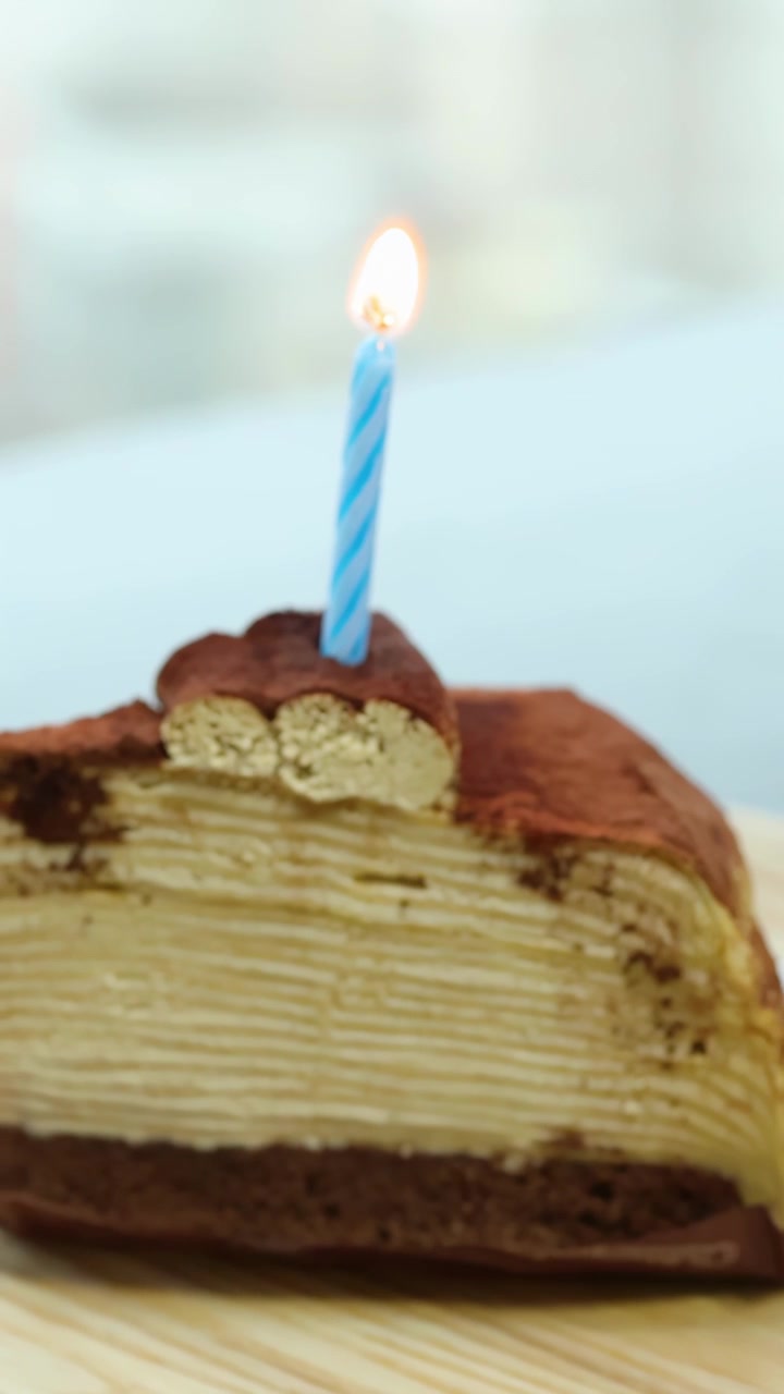 Mano che accende una candela di compleanno su una fetta di torta a strati