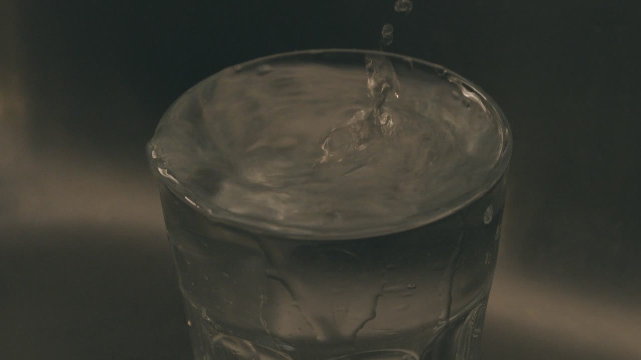 l'acqua cade in un dettaglio al rallentatore di vetro del vetro