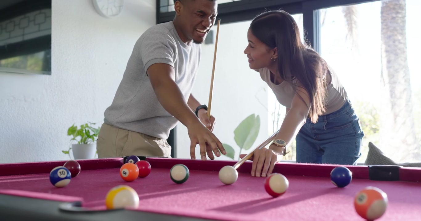 African American couple at magenta pool table practicing, man pointing guiding woman striking balls