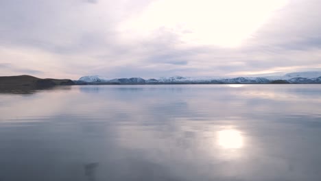 sunrise over lake myvatn in iceland, snowy mountains beyond the shore