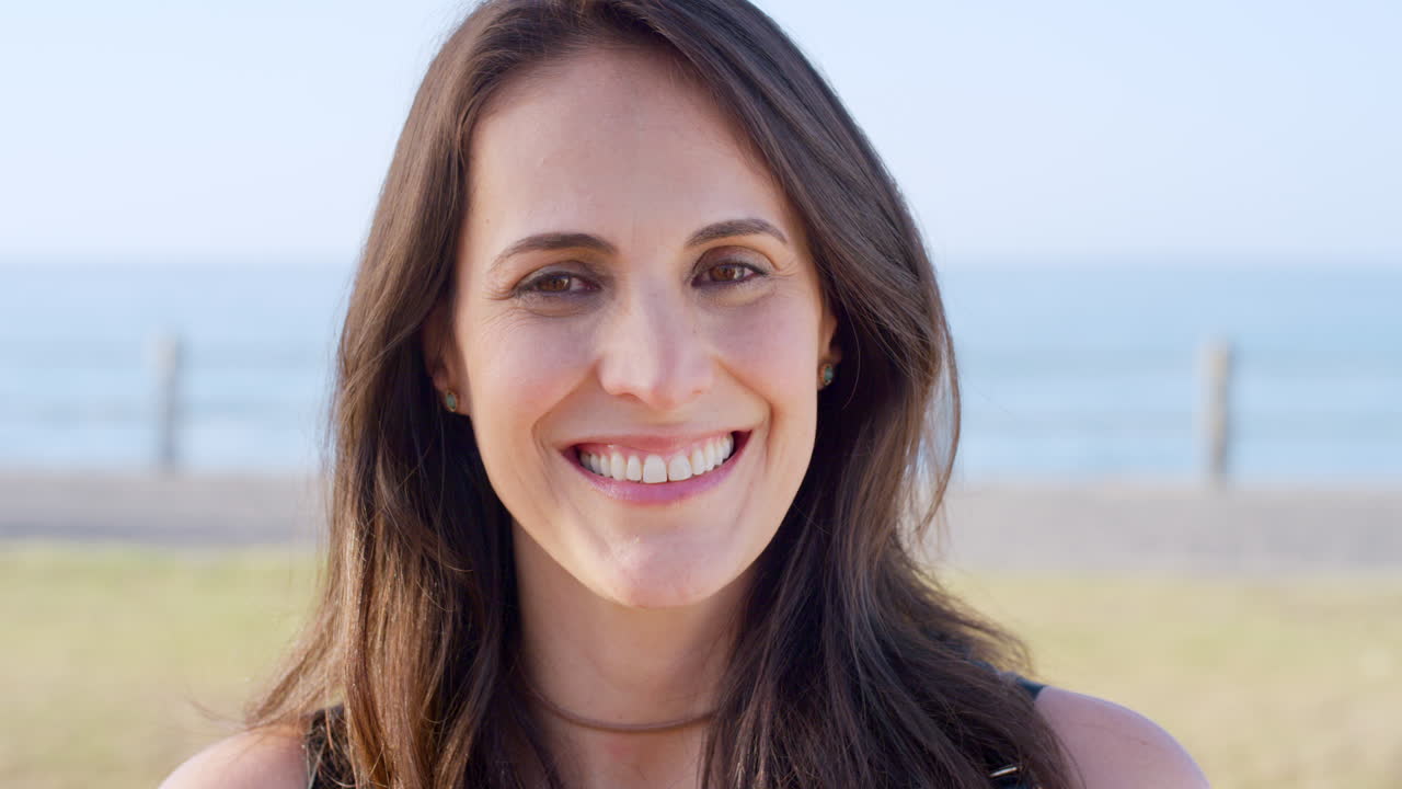 feliz, sonrisa y rostro de mujer en el parque de la playa