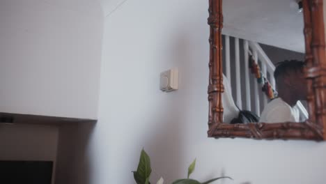 man adjusting the dial thermostat to lower the temperature to save money on energy bills during the cost of living crisis close up