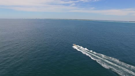 powerboat moving fast through ocean in sunny afternoon aerial forward tracking