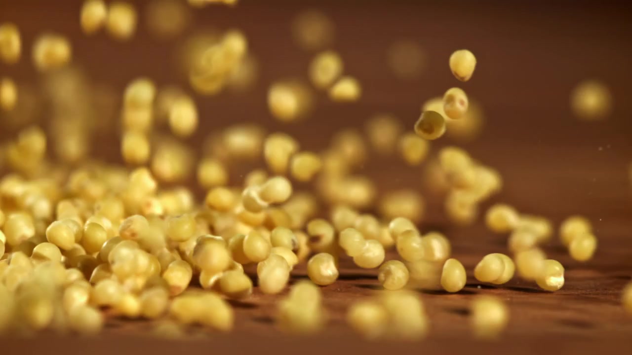 Millet Grains Falling onto a Wooden Surface in Slow Motion