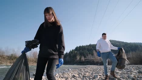 teamwork cleaning plastic on the beach. volunteers collect trash in a trash bag. plastic pollution and environmental problem concept. voluntary cleaning of nature from plastic. greening the planet