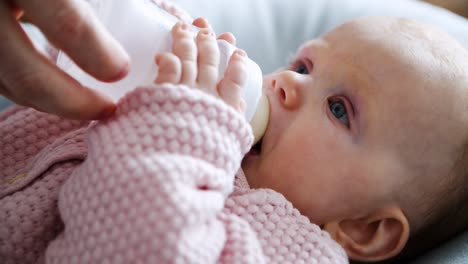 Eltern-Füttern-Ihre-Kleine-Tochter-Und-Geben-Eine-Flasche-Milch