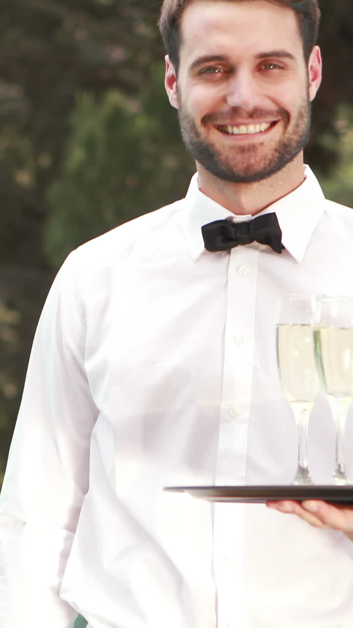 camarero sonriente sosteniendo copas de champán