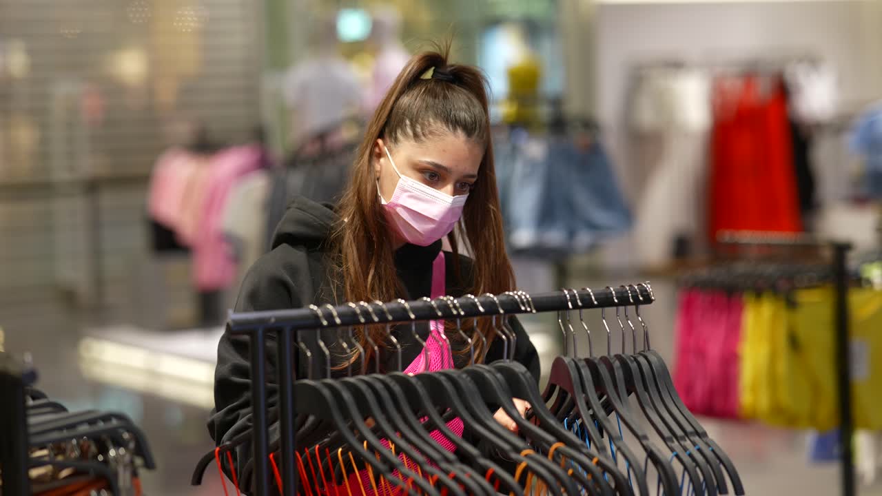 Donna che acquista vestiti in un negozio durante la pandemia di COVID-19
