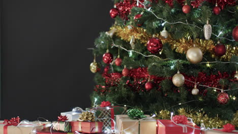 video of christmas tree with presents, baubles decorations and copy space on black background