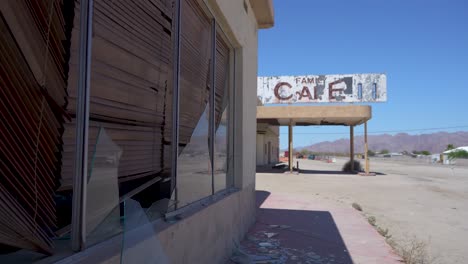 abandoned cafe with broken glass in california desert with mountains and blue sky in background