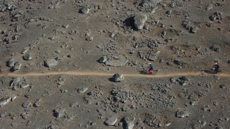 mountain bikers going downhill in a rocky hillside path